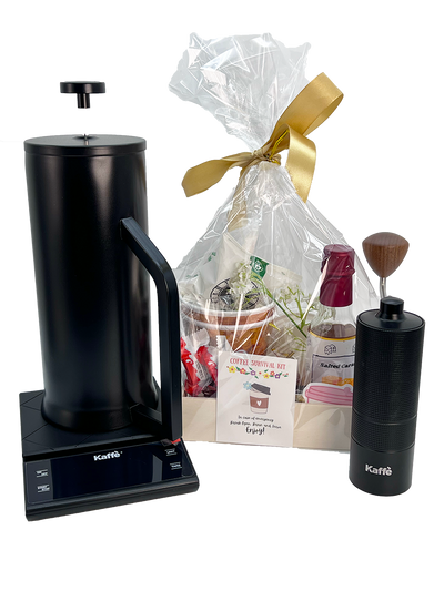 Black coffee press, gift bag with a gold bow, and Kaffee branded items on a white background
